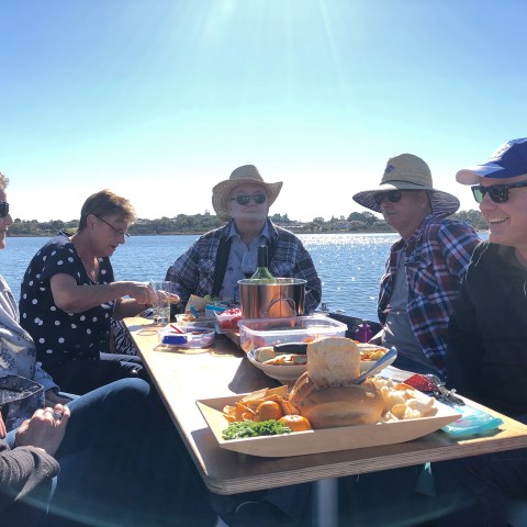 a group of people sitting at a table eating pizza