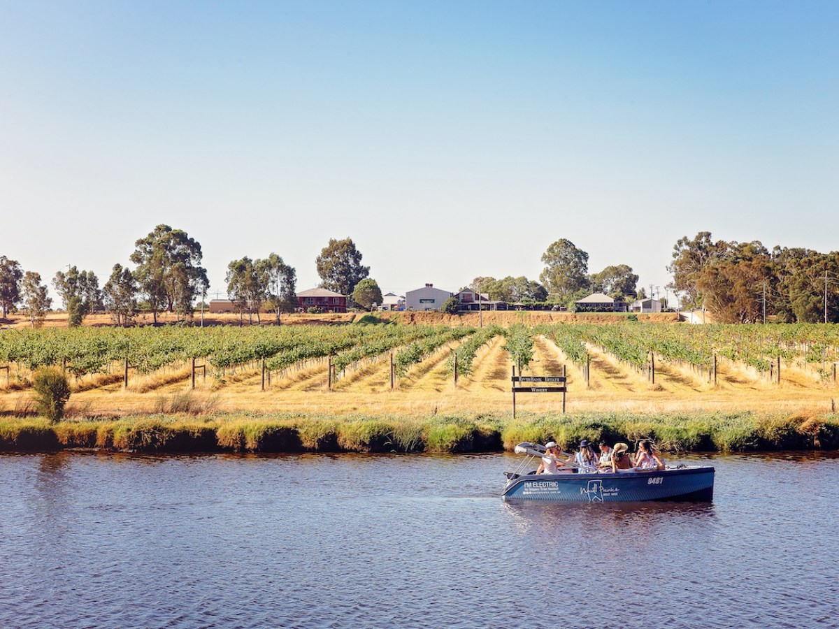 a small boat in a body of water next to a winery