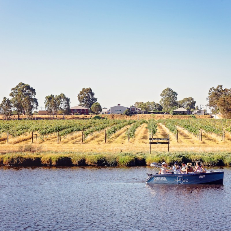 a small boat in a body of water next to a winery